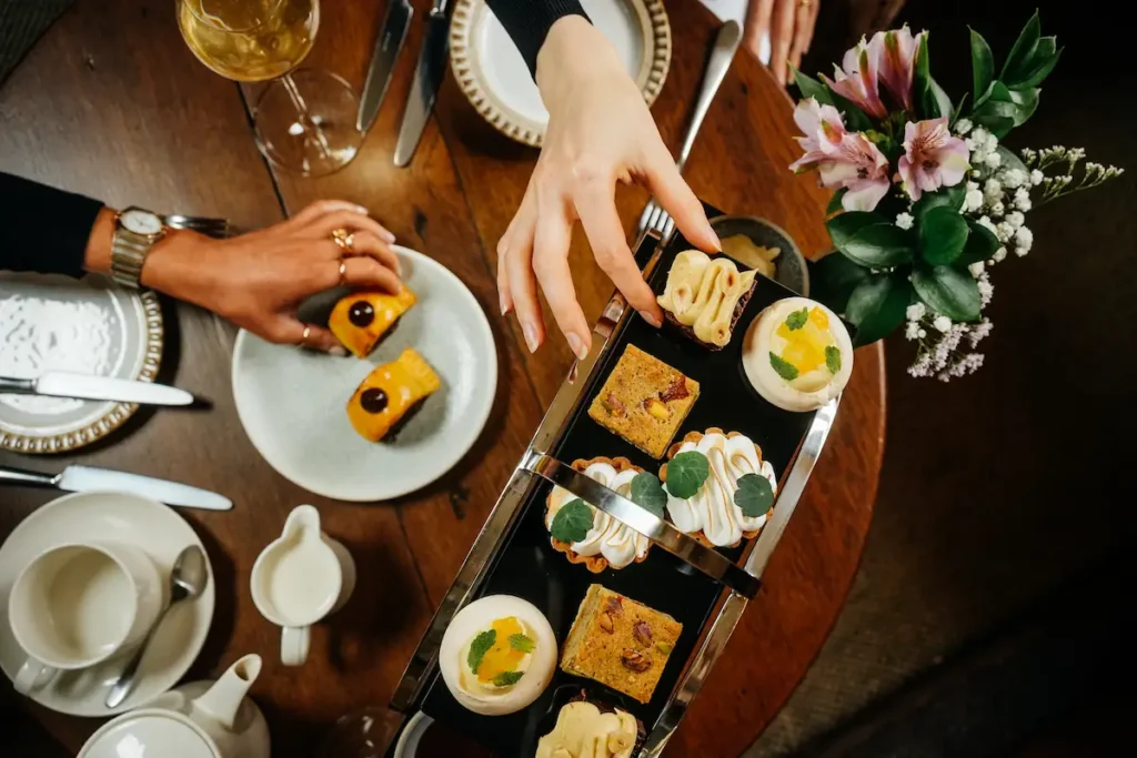 Two people grabbing items from the Afternoon Tea at The Peacock at Rowsley